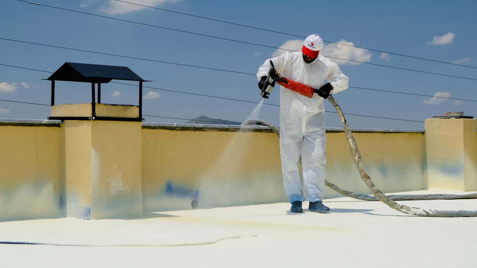 Roofer applying spray foam roofing on a flat commercial roof